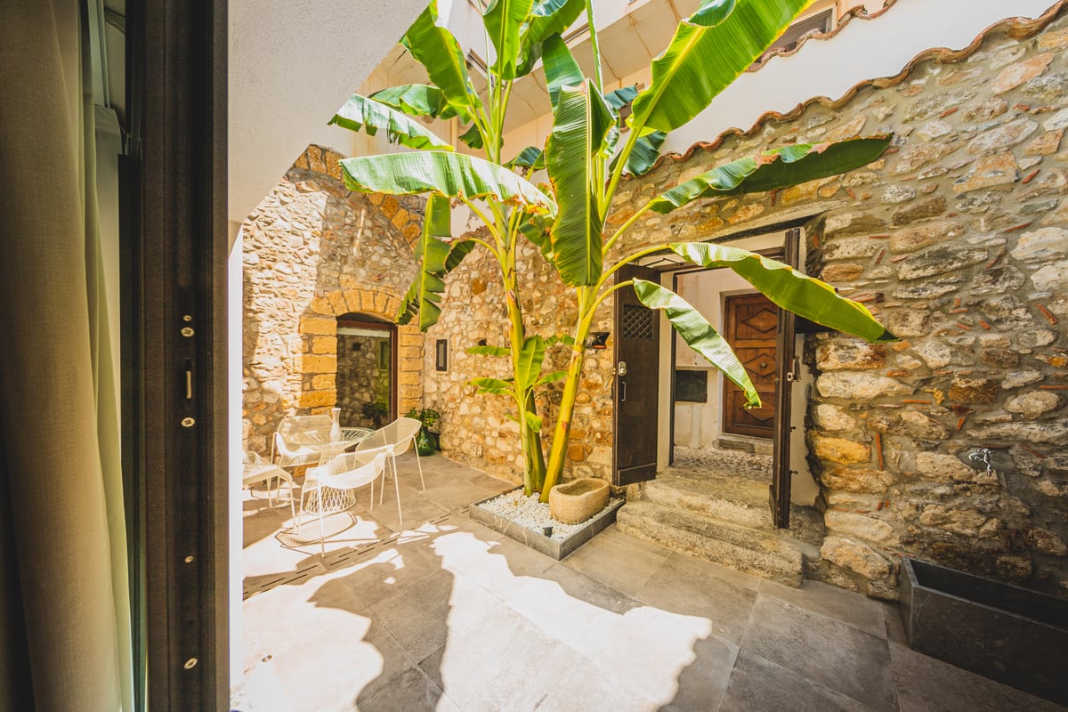 The courtyard in daylight, with a table, chairs and banana leaves.