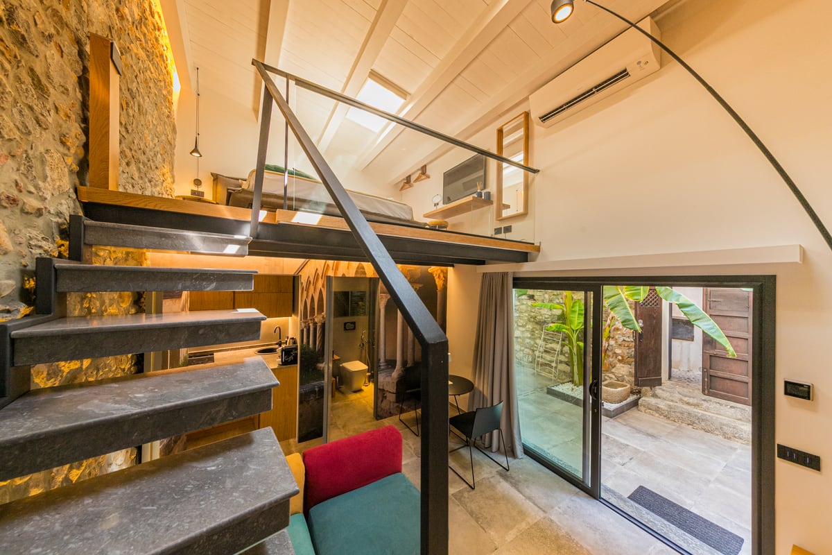 The wood and metal staircase connects the living area to the bedroom.