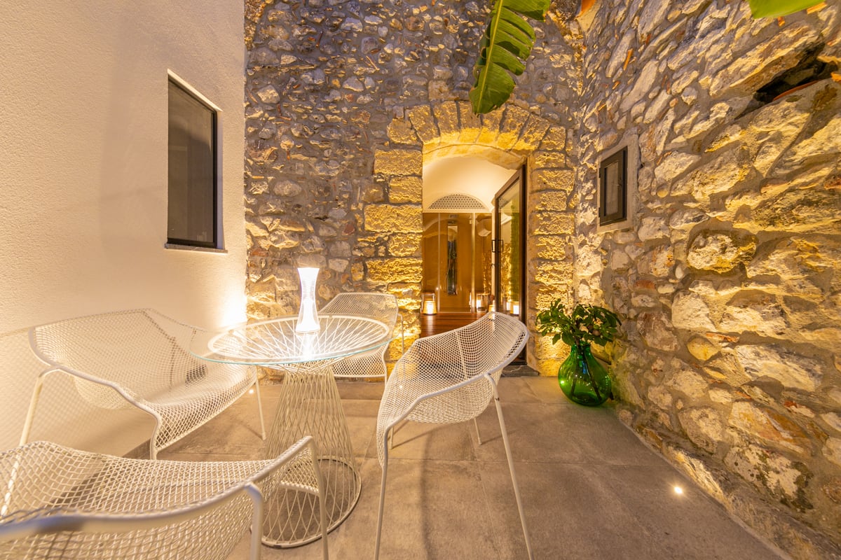 The table and transparent chairs in the softly lit evening courtyard.